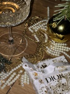 Elegant still life of champagne, pearls, and gifts for a luxurious holiday vibe.